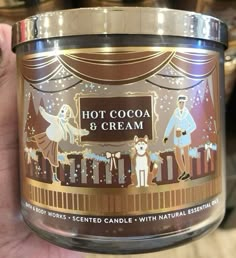 a person holding a candle in their hand that says hot cocoa and cream on it