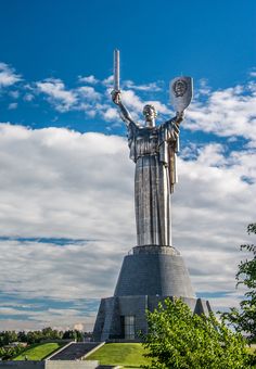 there is a statue that has a candle in it's hand and the sky behind it