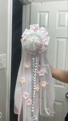 someone is holding up a hair comb decorated with flowers and ribbons in front of a door