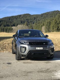 a grey range rover parked in front of a mountain