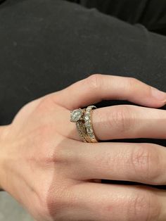 a woman's hand with two wedding rings on her left and the other hand holding an engagement ring