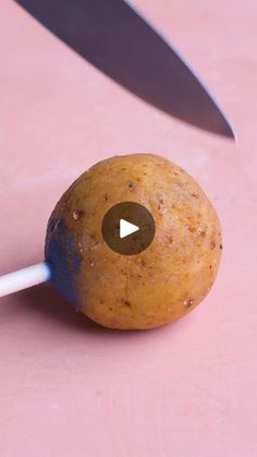 a potato with a knife sticking out of it's side on a pink surface