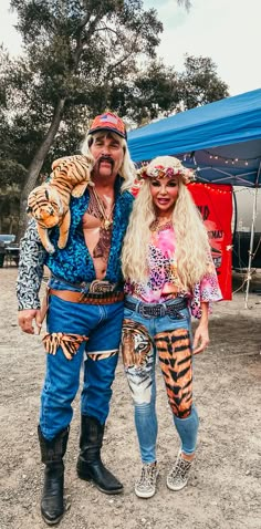 the man and woman are dressed up in costumes for an outdoor event with tents behind them