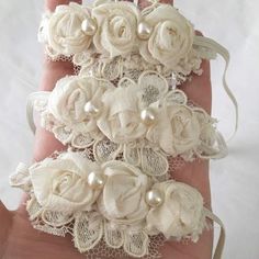 the hand is adorned with white lace and flowers, which are attached to pearls or garters