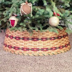 a christmas tree with ornaments hanging from it's branches in a wicker basket