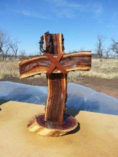 a wooden cross sitting on top of a table in the middle of an open field