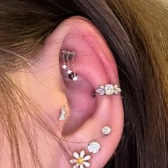 a woman with three different piercings on her ear and one has flowers in it