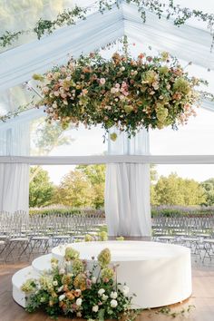 an outdoor wedding venue with white drapes and floral centerpieces on the ceiling