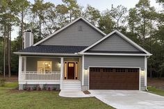 a gray house with two garages in the front and one on the side, surrounded by trees