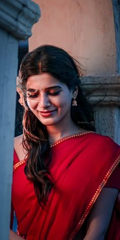 a woman in a red sari smiling and looking at the camera with her eyes closed