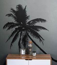 a palm tree painted on the side of a wall next to a cabinet with two jars