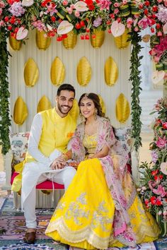 a man and woman posing for a photo in front of a decorated stage with flowers