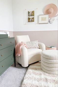 a baby's room with a white chair and green dresser