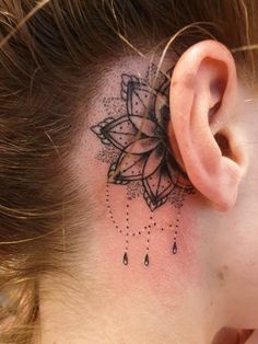 a woman's behind the ear has a black and white tattoo design on it