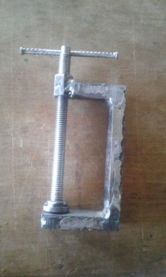 a square metal object sitting on top of a wooden table next to a wrench