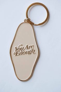 a keychain with the words you are enough written in gold foil on it