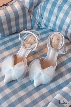 a pair of white high heeled shoes sitting on top of a blue and white checkered bed