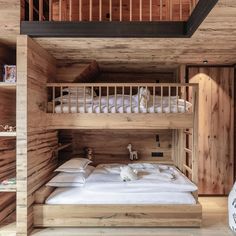 a bunk bed in a wooden room with white sheets and pillows on the bottom bunk