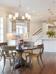 a dining room table with four chairs and a chandelier hanging from the ceiling