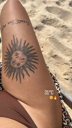 a woman's leg with a sun and moon tattoo on her left side, next to the beach