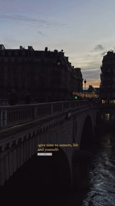 a bridge that is over some water with buildings in the background and a quote on it