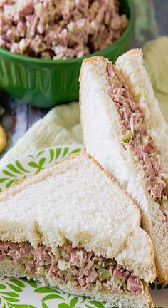 a sandwich cut in half sitting on top of a plate next to a bowl of food