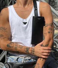 a man with tattoos on his arm holding a black bag