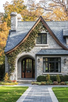 a stone house with ivy growing on the roof and front door, surrounded by lush green grass