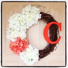 a wreath with white and pink flowers on the front door is decorated with a red letter