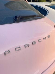 a pink car parked next to another white car with the word porsche written on it