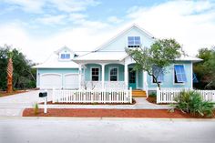 a blue house with white picket fence and trees