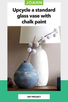 a blue vase sitting on top of a wooden table next to a white lampshade