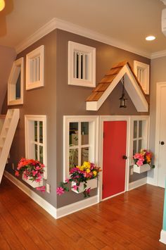 a kid's house with flowers in the window boxes and stairs leading up to it