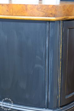 an old blue painted cabinet with gold trim and wood grain detail on the top part