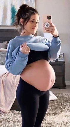 a pregnant woman taking a selfie with her cell phone