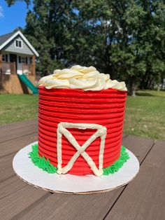 a cake made to look like a red barrel with a white barn in the background