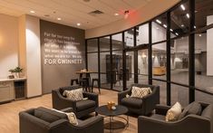 a room with couches, chairs and tables in front of glass walls that have writing on them