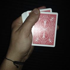 a hand holding two playing cards in the dark