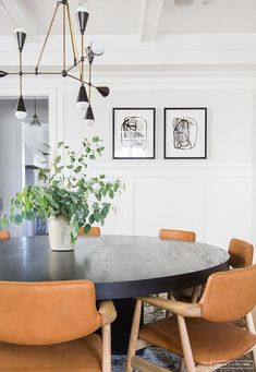 a dining room table with four chairs and a potted plant on the top shelf