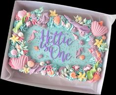 there is a cake decorated with shells and seahorses on the top it says,'heftie is one '