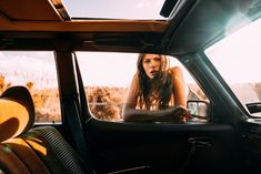 a woman sitting in the driver's seat of a car looking out the window