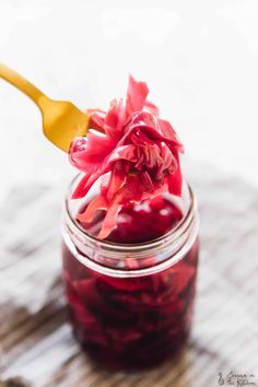 a jar filled with cranberry sauce on top of a wooden table next to a spoon