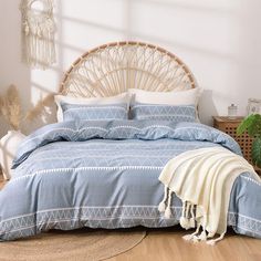 a bed with blue comforter and pillows in a room next to a plant on the floor