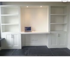 an empty room with white bookcases and black slate flooring on the walls