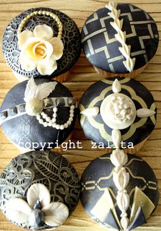 four decorated cupcakes sitting on top of a wooden table