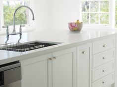 a white kitchen with a sink, dishwasher and window in the back ground