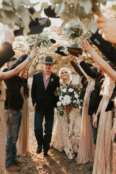 a bride and groom are surrounded by their wedding party as they walk down the aisle