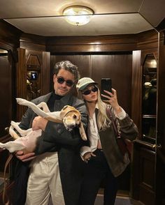 a man and woman taking a selfie with their dogs in the elevator at an airport