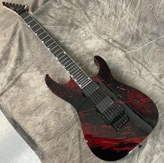 a red and black guitar laying on top of a sheet