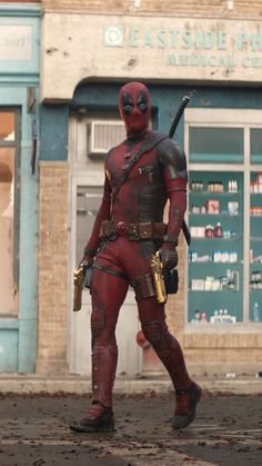 a man dressed as deadpool is walking down the street in front of a store